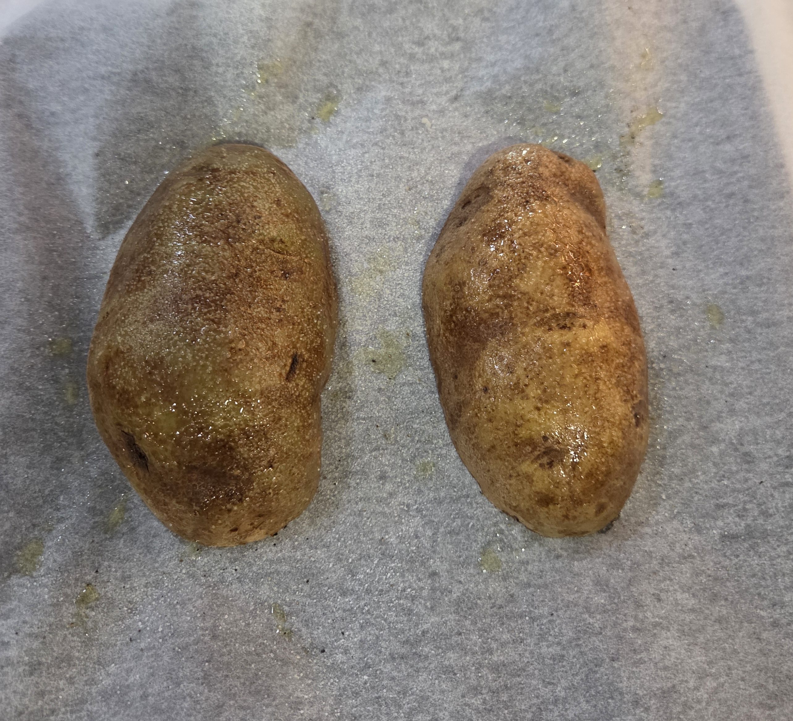 Potato halves placed flesh side down on a baking sheet