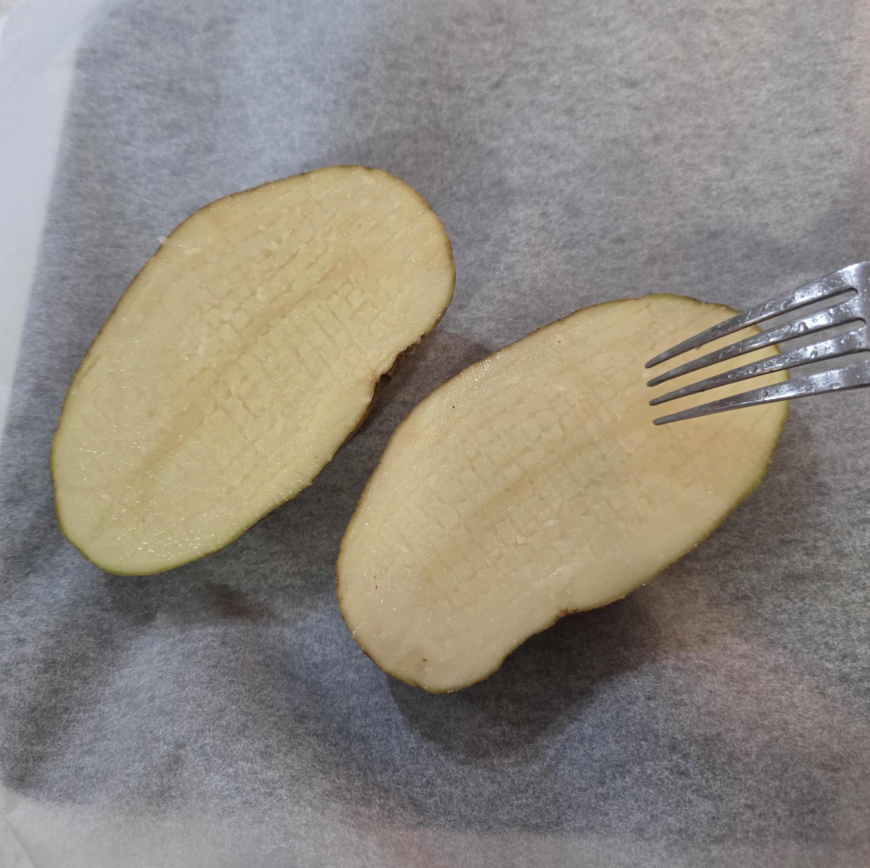 Scoring the potato flesh in a criss-cross pattern with a fork